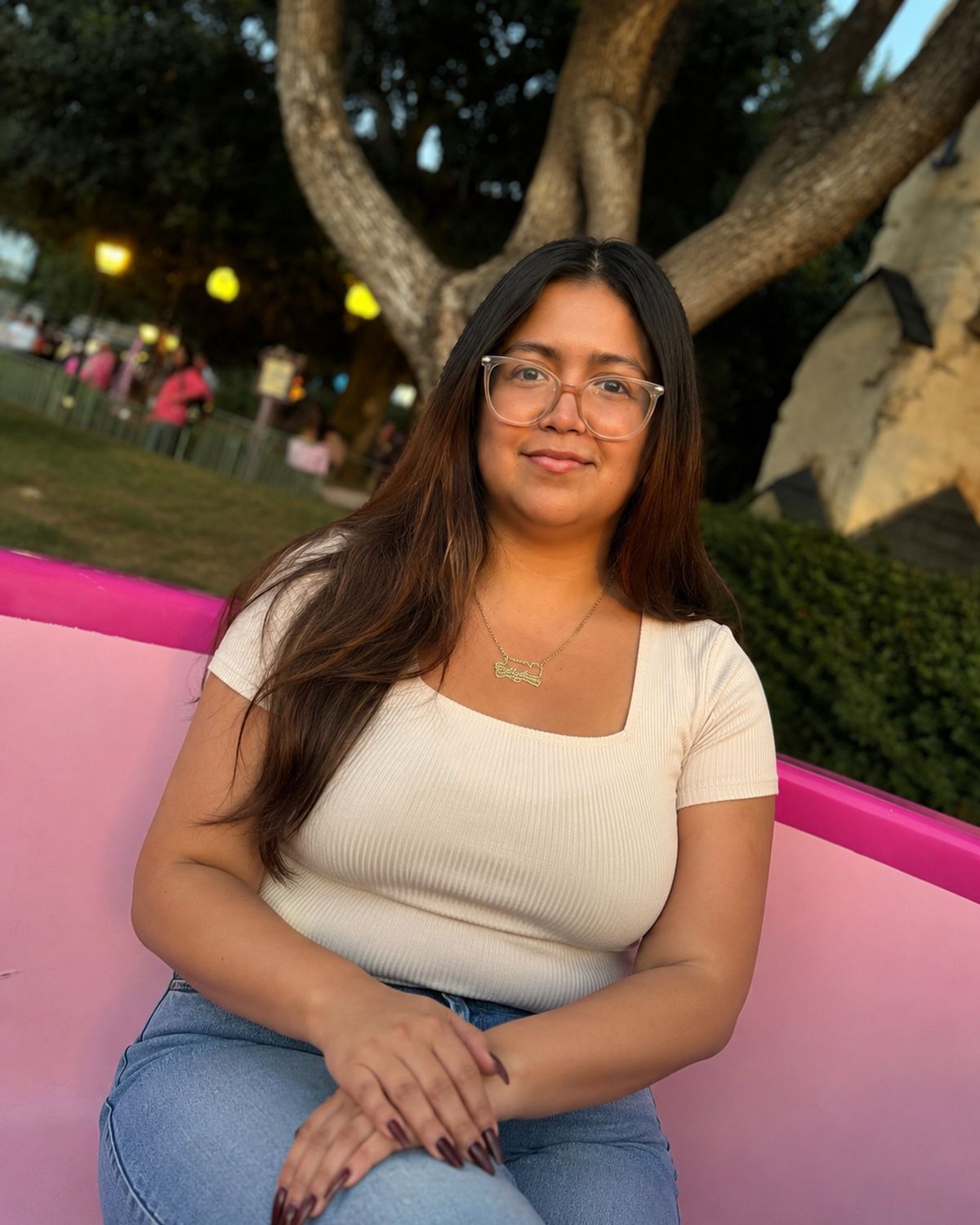 Crystal sitting on a pink bench at the park at golden hour