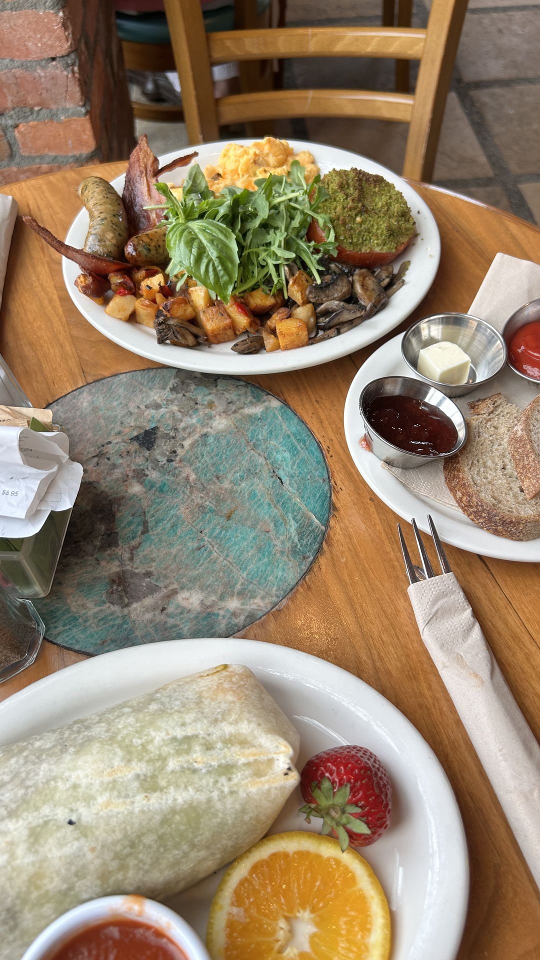 Overhead shot of a brunch table with eggs, burrito and fresh fruit